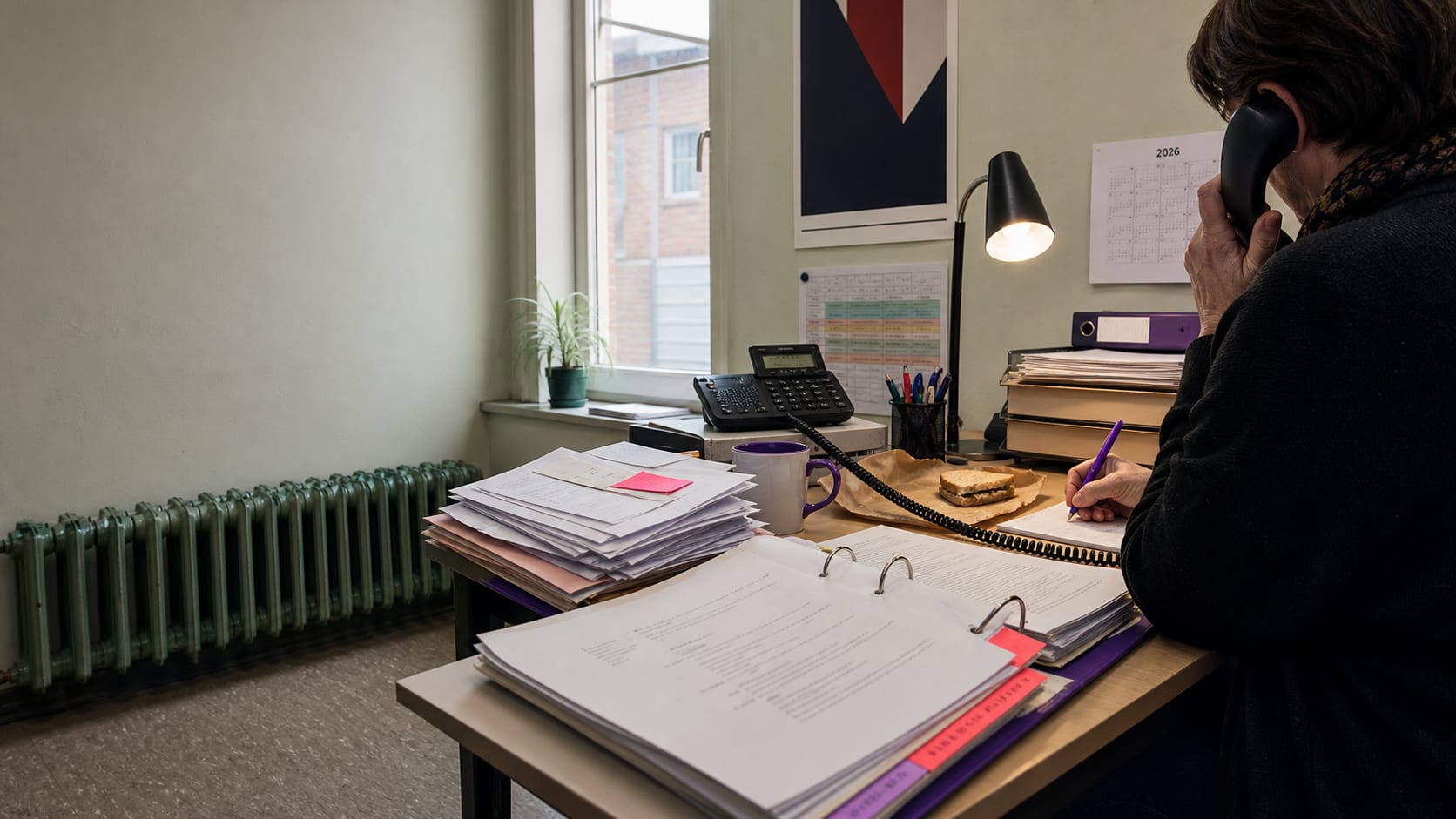 Anonyme Bürokraft einer Gewerkschaft am Telefon nach einem frischen Tarifabschluss, neben offenem Ordner mit Mitgliederanfragen.